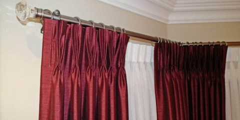 Bay window with luxurious curtains, sheers and iron curtain rods with crystal finials