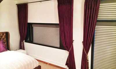Purple curtains with remote control blinds in the master bedroom.