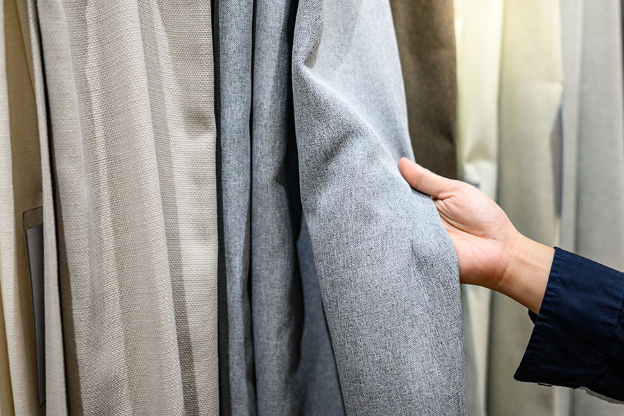 Male hand choosing color and texture of curtain samples in furni